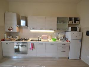 una cucina con armadietti bianchi e frigorifero bianco di Cozy Holiday Home with Terrace in Carrara a Carrara