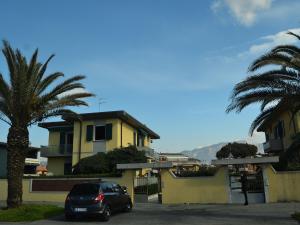 un'auto parcheggiata di fronte a una casa gialla con palme di Cozy Holiday Home with Terrace in Carrara a Carrara