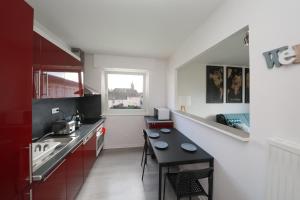 a kitchen with red cabinets and a black table at L'étoile du Nord - 1 PARKING GRATUIT in Colmar