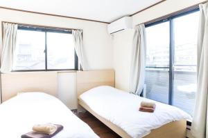 two beds in a room with large windows at Tokyo Aoto House in Tokyo