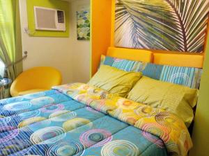 uma cama com um edredão colorido num quarto em Nica's Place Property Management Services at Horizons 101 Condominium em Cebu