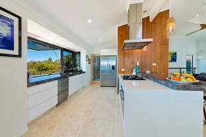 a large kitchen with white counters and a large window at Panorama Beach House in Bonny Hills
