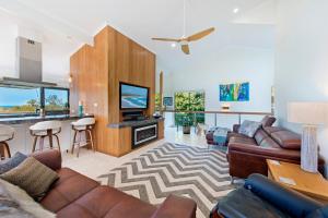 Panorama Beach House في Bonny Hills: غرفة معيشة مع كنب ومطبخ مع بار