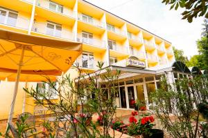 a hotel with an umbrella and flowers in front of it at Solaris Hotel in Balatonföldvár