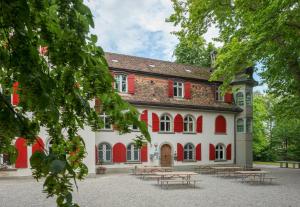 um edifício com persianas vermelhas e mesas à sua frente em Schaffhausen Youth Hostel em Schaffhausen
