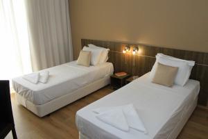duas camas num quarto de hotel com lençóis brancos em Sea & Hill Guest Houses хотелски тип em Lozenets