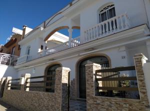 ein weißes Haus mit Balkon darüber in der Unterkunft Hostal Los Arcos in Chipiona