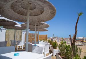 a patio with tables and chairs and umbrellas on the beach at Garden Hotel Ripa in Vieste