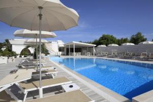 a pool with chairs and umbrellas next to a building at Garden Hotel Ripa in Vieste