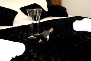 a bottle of wine and two glasses on a bed at Apartments Prestige in Split