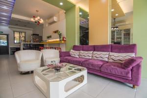 sala de estar con sofá púrpura y sillas blancas en Little SkyLark B&B, en Magong