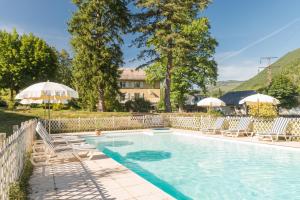 a swimming pool with lounge chairs and umbrellas at Hôtel du Val d'Aure in Cadéac