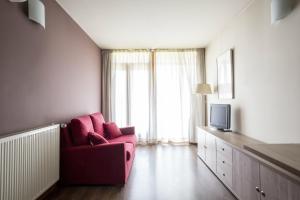ein Wohnzimmer mit einem roten Stuhl und einem TV in der Unterkunft Residencia Universitaria Hernan Cortes in Salamanca