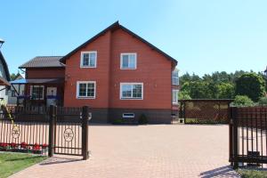 a red brick house with a black fence at Svečių Apartamentai Vanagupėje in Palanga