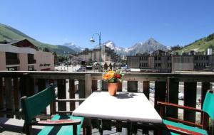 a table with a vase of flowers on a balcony at Hotel le Sherpa in Les Deux Alpes