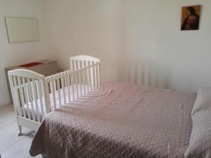 a bedroom with a crib and a bed with a blanket at Sa Domu e Muru in Galtellì