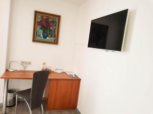 a desk with a television on a wall with a chair at Hotel Bischof in Dornbirn
