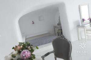 a bedroom with a bed and a chair and a vase of flowers at Pearl on the Cliff Hotel & Suites by Pearl Hotel Collection in Imerovigli
