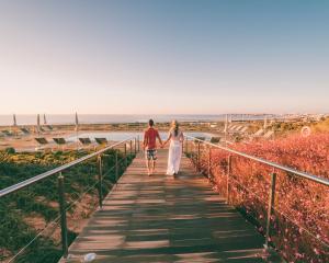 a man and woman walking down a boardwalk at Palmares Beach House Hotel - Adults Only in Lagos