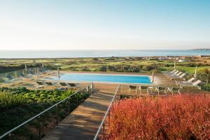 a staircase leading to a pool with the ocean in the background at Palmares Beach House Hotel - Adults Only in Lagos