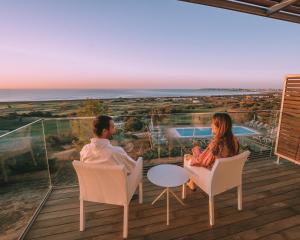 a man and woman sitting on a balcony looking out at the ocean at Palmares Beach House Hotel - Adults Only in Lagos