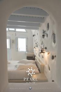 a bedroom with a bed and a wall with rocks at Pearl on the Cliff Hotel & Suites by Pearl Hotel Collection in Imerovigli