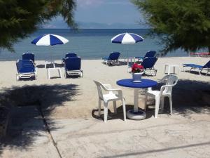 un tavolo con sedie e ombrelloni sulla spiaggia di Rooms Ntontas a Prinos