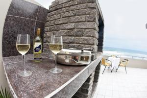 two glasses of white wine on a balcony with a view of the ocean at First Group Desert Rose in Hentiesbaai