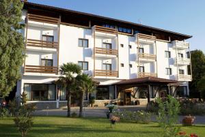 a large white building with trees in front of it at Rodopi Hotel in Komotini