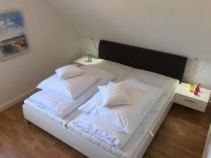 uma cama branca com lençóis brancos e almofadas em Friesengut4 em Langeoog