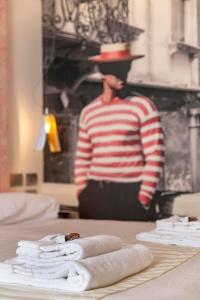 a man in a hat standing behind a table with towels at Ca' de la Fonte - WENICE Deep Culture in Venice
