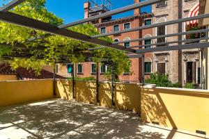 a balcony with a yellow wall and trees and a building at Ca' de la Fonte - WENICE Deep Culture in Venice