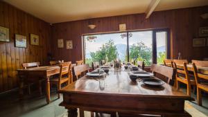 a dining room with a long table and a large window at Cedar Lodge By Aahma in Rāmgarh