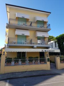 un gran edificio amarillo con balcones y mesas en Hotel Margot en Lido di Camaiore