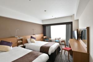una camera d'albergo con due letti e una televisione di Hotel Granvia Hiroshima a Hiroshima
