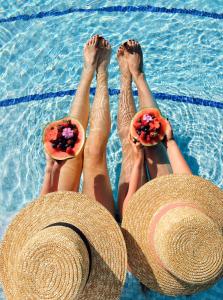 a group of people laying in a swimming pool with hats at Villa Nicolli Romantic Spa Resort - Adults Only in Riva del Garda