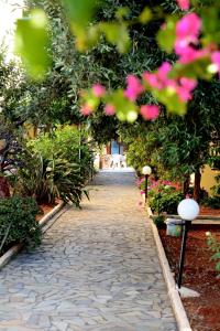 um caminho de pedra num jardim com flores cor-de-rosa em Alex Home Apartments em Hersonissos