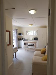 Settler Cottage Apartment في غراهامستاون: غرفة معيشة مع أريكة ومطبخ