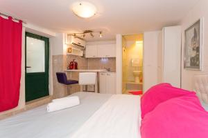 a bedroom with a white bed and a kitchen at Studio Varos in Split