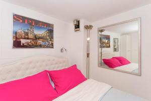 a bedroom with a bed with pink pillows and a mirror at Studio Varos in Split