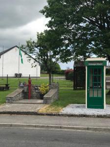 a green phone booth sitting on the side of a street at Dream Cottage in Ballintober