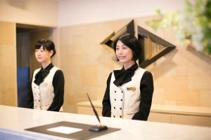 a woman standing in front of a counter in a mirror at Hotel nanvan Yaizu in Yaizu