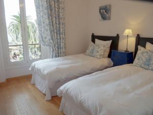 two beds in a room with a window at Hotel La Regence in Villefranche-sur-Mer