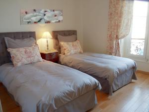 a bedroom with two beds and a lamp and a window at Hotel La Regence in Villefranche-sur-Mer
