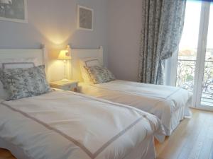 two beds in a room with a window at Hotel La Regence in Villefranche-sur-Mer