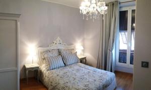 a bedroom with a white bed with two tables and a chandelier at Hotel La Regence in Villefranche-sur-Mer
