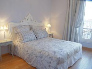 a bedroom with a white bed with two lamps and a window at Hotel La Regence in Villefranche-sur-Mer