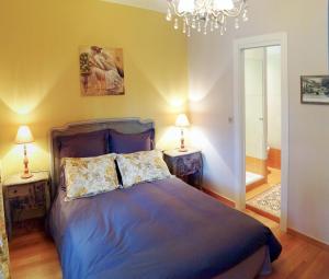 a bedroom with a blue bed with two lamps and a chandelier at Hotel La Regence in Villefranche-sur-Mer