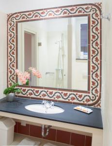 a bathroom with a sink and a large mirror at Hotel La Regence in Villefranche-sur-Mer