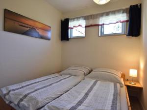 a bedroom with two beds and two windows at Peaceful Bungalow in Diedrichshagen near Baltic Sea in Diedrichshagen